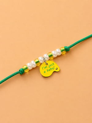 A beaded dog paw rakhi featuring yellow and ehite pearl beads with a small yellow tag that reads 'I'm just a baby' 